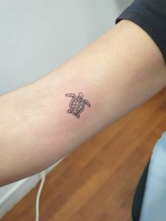 a small turtle tattoo on the arm