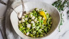 a white bowl filled with green beans and cheese on top of a marble countertop