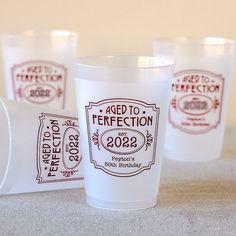 three shot glasses sitting next to each other on top of a carpeted floor with red and white labels