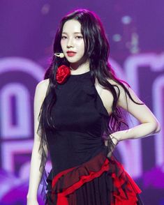 a woman with long black hair wearing a red and black dress on the catwalk