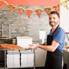 a man in an apron is holding a pizza