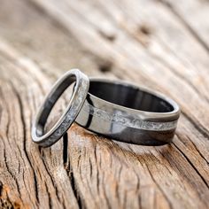 two wedding rings sitting on top of an old wooden table with grainy woodgrains