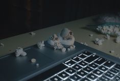 a laptop computer sitting on top of a wooden table next to a bowl of popcorn