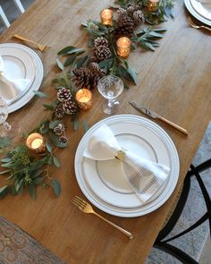 the table is set with pine cones, candles and greenery for an elegant look