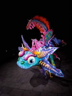 a colorful dragon statue sitting on top of a stone floor next to a black wall