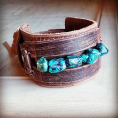 Distressed Finish Leather Cuff features a genuine strand of chunky African Turquoise. Each strand is different and will show varying shades of the natural stone. ***Please view all the pictures as they show examples of the many stone colors Cuff measures 2" by 9" in length Adjustable to 7" and 7.5" Although your item will resemble the photo, each piece is created by hand, so no two are identical.Thank you for visiting The Jewelry Junkie! Adjustable Turquoise Bracelets With Patina, Adjustable Turquoise Bracelet With Patina, Adjustable Turquoise Leather Bracelet In Rustic Style, Adjustable Rustic Turquoise Leather Bracelet, Rustic Turquoise Jewelry For The Beach, Bohemian Turquoise Cuff Bracelet With Patina, Rustic Handmade Turquoise Cuff Bracelet, Turquoise Bohemian Cuff Bracelet With Patina, Southwestern Adjustable Cuff Bracelet With Natural Stones