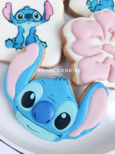 some decorated cookies on a white plate with blue and pink frosting, including an image of stitcher from the disney movie