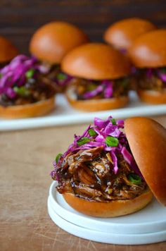 pulled pork sliders with coleslaw and red cabbage on a white platter