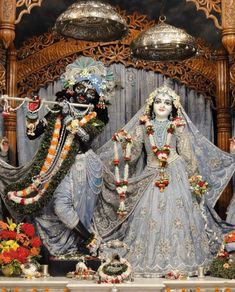 an idol is displayed in front of a stage decorated with flowers and garlands on it