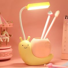 a little snail lamp sitting on top of a desk next to a toy horse and other items