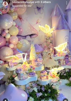 there is a cake table with fairy land on it and balloons all around the place