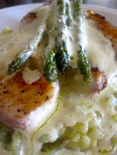 a white plate topped with chicken and asparagus covered in gravy