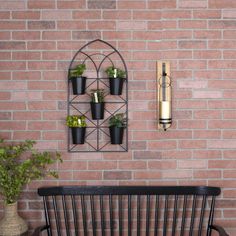 a black bench sitting in front of a brick wall with potted plants on it