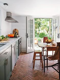 a kitchen with an open door leading to the dining room and patio area, along with brick flooring