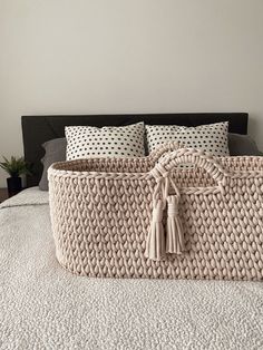 a large woven basket sitting on top of a bed next to pillows and pillow cases