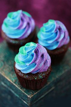 three cupcakes with blue and purple frosting