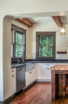 a kitchen with an island made out of wooden planks and white cabinets, along with black counter tops