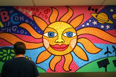 a man standing in front of a colorful mural