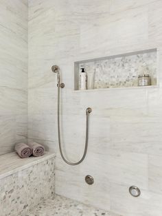 a bathroom with marble walls and flooring, including a walk in shower next to a white tiled wall