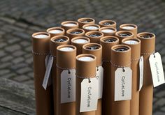 several rolls of brown paper with labels on them sitting on a wooden table next to a brick walkway