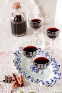 two glasses of red wine sit on a plate next to cinnamon sticks and an empty bottle