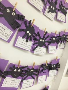 purple and black paper bats are hanging from clothes pins on a line with words written below them