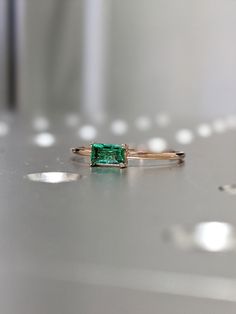 an emerald ring sitting on top of a table