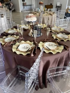 the table is set with clear chairs and brown linens for an elegant wedding reception