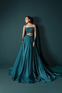 Teal net choli with illusion full sleeves, attached draped detail (can be made as a dupatta on request), paired with a silk lehenga. Explore the latest trends in wedding lehenga choli, diverse collections, and outfit options for brides-to-be.In a captivating shade of teal, this lehenga choli ensemble is a vision of sheer elegance. The net choli features an enchanting illusion neckline and full sheer sleeves, lavishly hand-embellished with gradients of sequins and Swarovski crystals, intricately Trending Lehenga Designs, Sea Green Lehenga, Green Lehenga Choli, Simple Lehenga, Trendy Outfits Indian, Indian Outfits Lehenga, Lehenga Designs Simple, Green Lehenga, Choli Designs