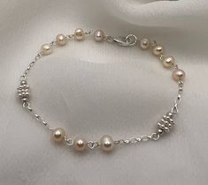 This delicate yet striking bracelet is the perfect gift for the festive season.  It's made to match the Dinky Short Necklace in Pale Peach but can be worn alone.  Alternatively stack it with our other bracelets.  If you don't want to gift it then get it for yourself as a payday treat! The potato pearls measure approximately 4mm and is combined with bright sterling silver daisy spacers and linked together with fine sterling silver rolo chain.  The total length of the bracelet is 17.5cm including the sterling silver clasp.  It will be sent to you in an attractive eco friendly presentation box.  If you have any queries, please do message me. Follow on Instagram @jewelsbyneeta_ Thanks for visiting my shop, Neeta Adjustable Hand-strung Sterling Silver Bracelet Gift, Silver Single Strand Beaded Bracelets As Gift, Silver Single Strand Beaded Bracelet Gift, Silver Single Strand Bracelet As Gift, Adjustable Sterling Silver Bracelet With Lobster Clasp As Gift, Adjustable Single Strand Pearl Bracelet As Gift, Delicate Adjustable Bracelets With Lobster Clasp, Silver Single Strand Pearl Bracelet Gift, Silver Single Strand Pearl Bracelet As Gift