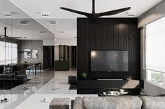 a modern living room with black and white walls, ceiling fan and couches in front of a flat screen tv