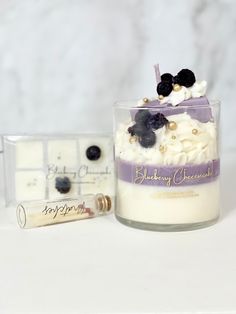 a candle with some blackberries in it next to a tube of cream