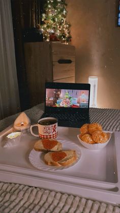 a laptop computer sitting on top of a white tray filled with food and coffee cup