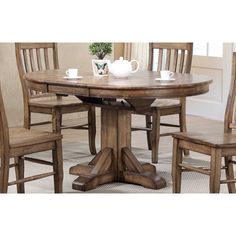 a wooden table with chairs around it and a vase on the table top in front of it