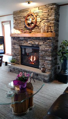 a living room with a stone fireplace and glass table in front of the fire place