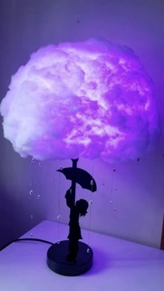 a lamp that has a cloud on top of it and is lit up with purple light