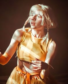 a woman with blonde hair wearing a yellow outfit and holding a microphone in her hand