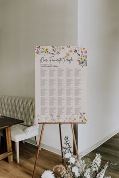 a seating chart is placed on an easel next to flowers