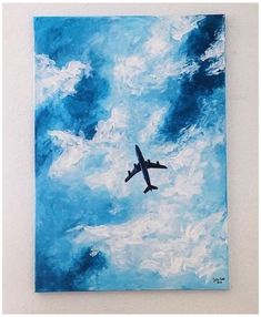 an airplane is flying in the sky above some clouds and blue paint on a white wall