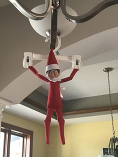 an elf is hanging from the ceiling with his arms and legs