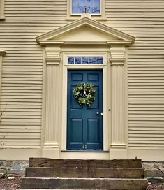 a blue front door with a wreath on it and steps leading up to the house