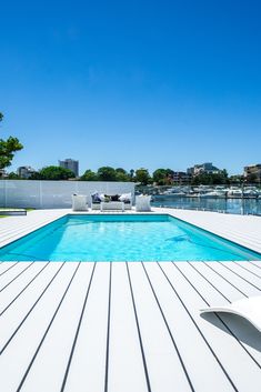 an empty swimming pool with lounge chairs on the deck and water in the back ground