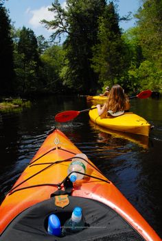 two people in kayaks paddling down a river