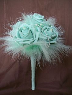 a bridal bouquet with pearls and feathers on a brown cloth background in the shape of a rose