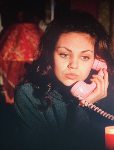 a young woman talking on a pink telephone