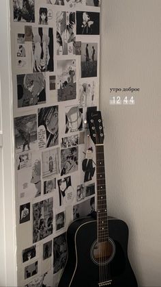 a black guitar sitting in front of a wall with pictures on it