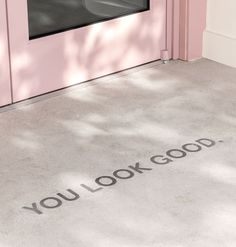 you look good written on the floor in front of a pink door with a window