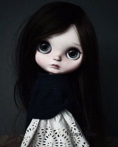 a close up of a doll wearing a black and white dress with long dark hair