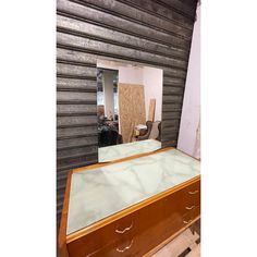 a large mirror sitting on top of a wooden dresser next to a wall covered in wood planks