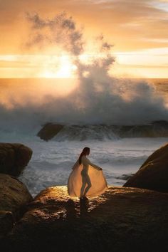 a woman standing on top of a rock next to the ocean